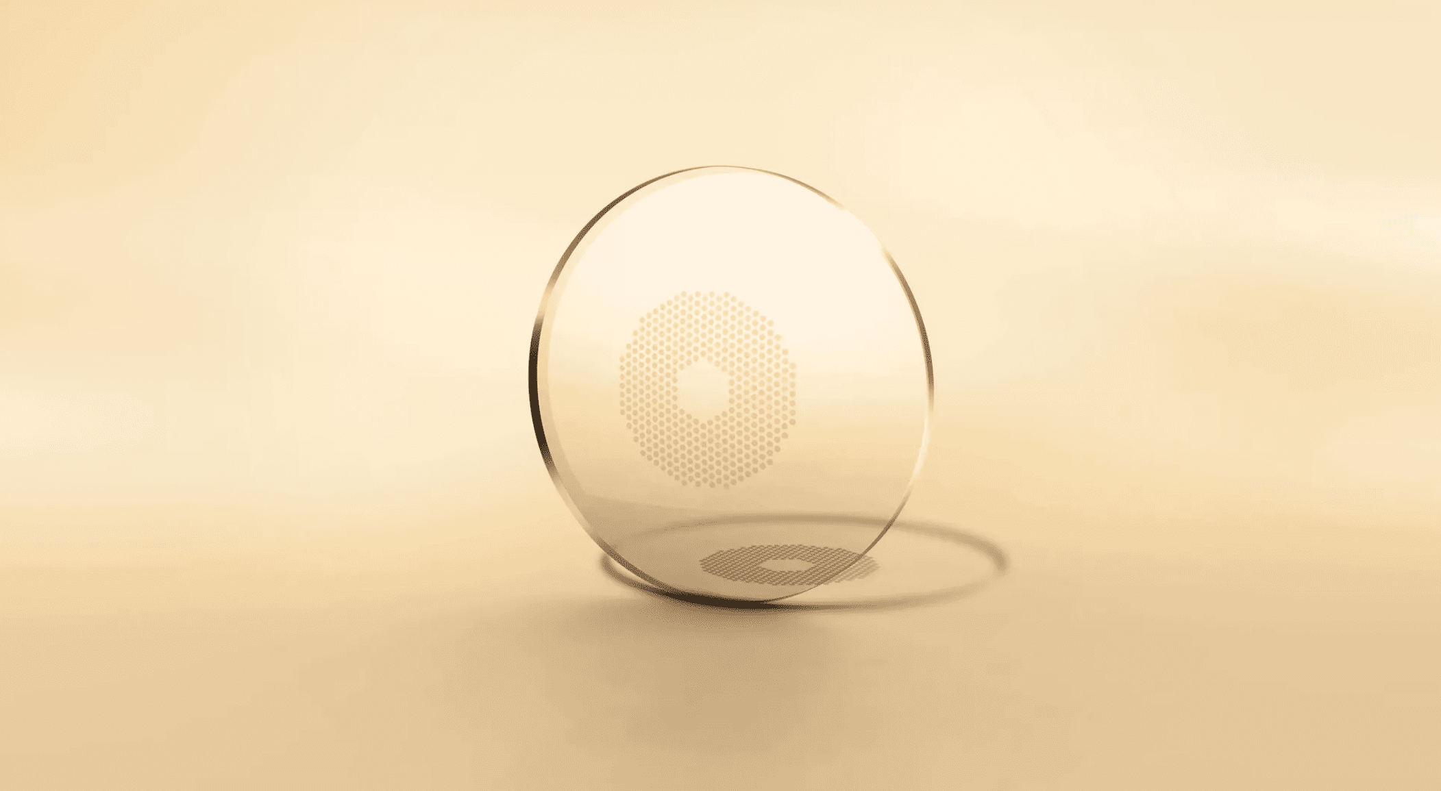 A transparent contact lens with a faint geometric pattern in the center is placed upright on a smooth, beige surface, casting a soft shadow. The background is a gradient of light beige tones.